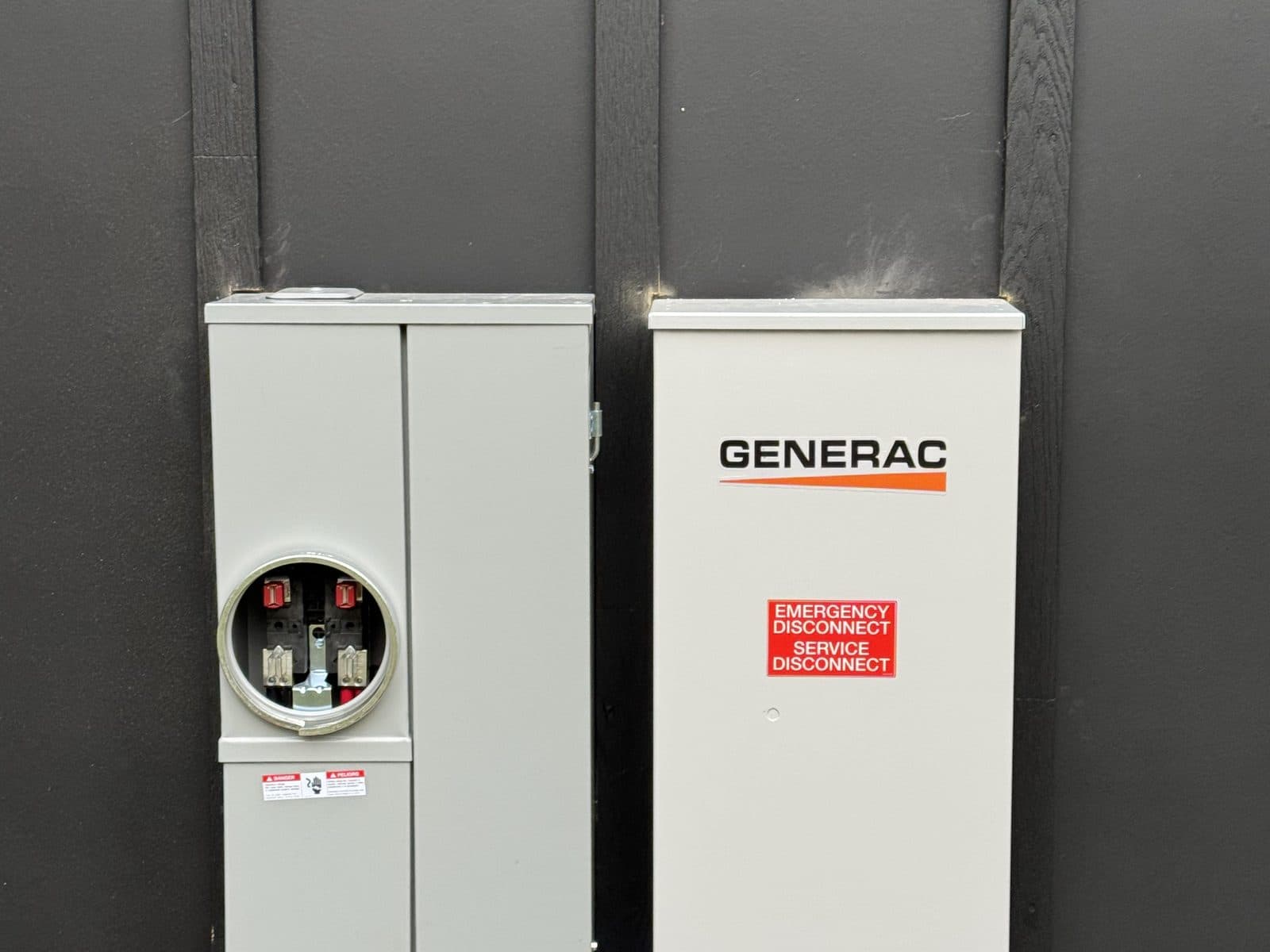 Generac transfer switch and meter installed on dark home siding